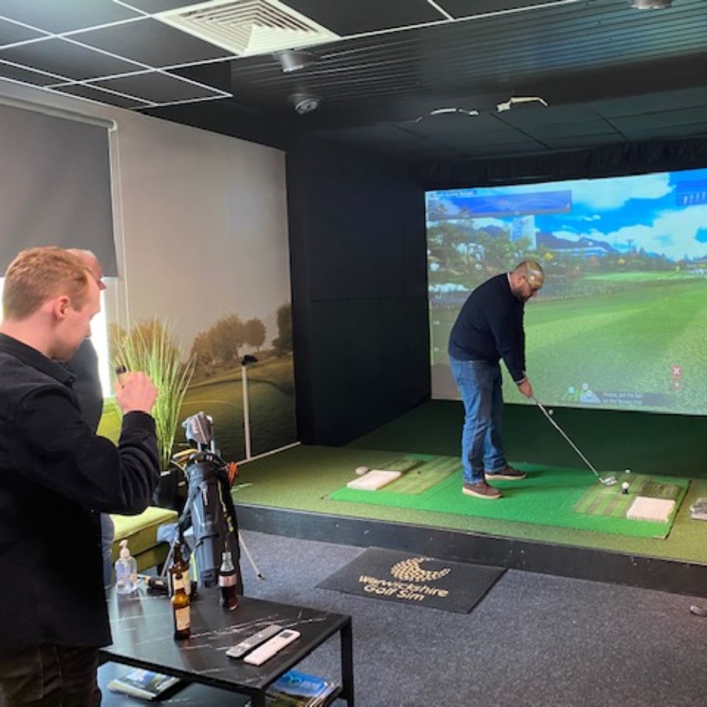 how_do_golf_simulators_work__3_guys_standing_around_a_golf_simulator