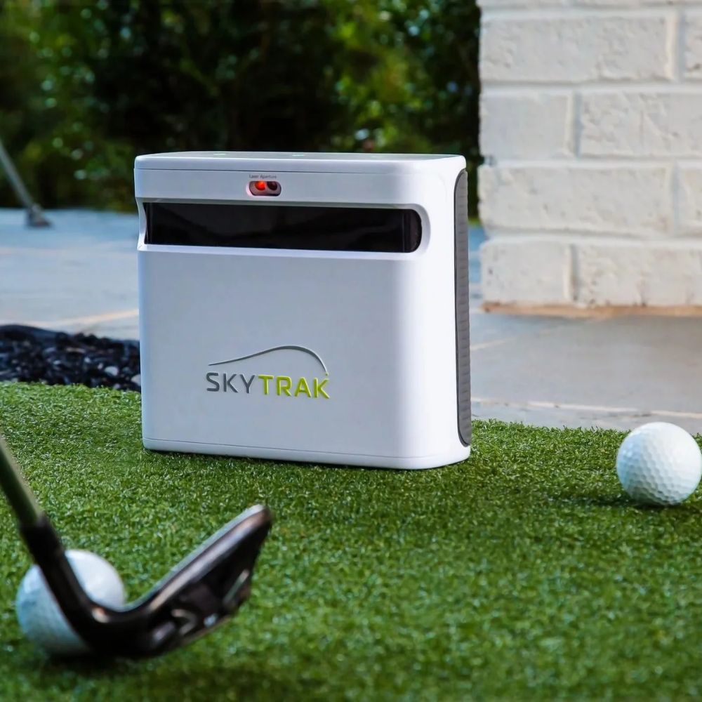 skytrak_launch_monitor_sitting_next_to_a_golf_mat_with_multiple_balls